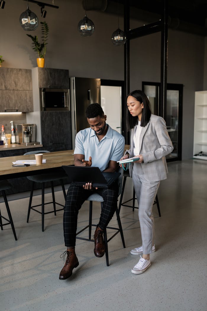 our-services-1 Two professionals engaged in a business discussion in a stylish, contemporary office setting.